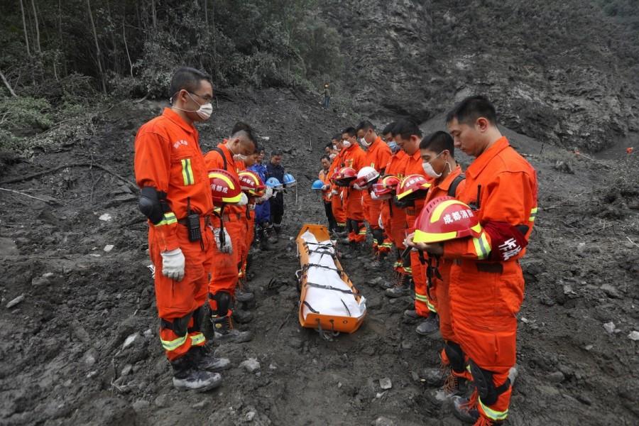Rescue workers stand in silent tribute before evacuating a body from the site of a landslide in the village of Xinmo, Mao County, Sichuan Province. Landslide buries Chinese village,Chinese village,Sichuan province,Xinmo village,Xinmo village China landslide