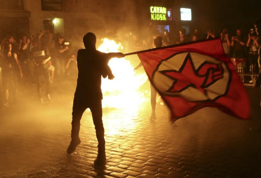 An anti-G20 protester waves a flag in front of burning garbage outside the Rote Flora building in the alternative Hamburg Schanze district following clashes with German riot police in Hamburg. G20 protests,G20,G20 protests Germany,clash in Germany,G20 summit