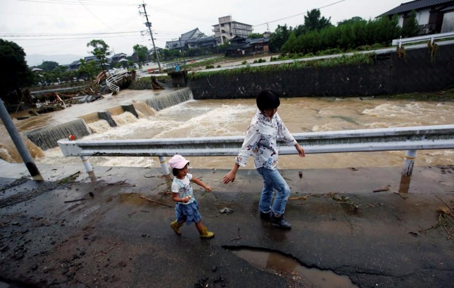 Local residents walk in an area damaged by swollen river after heavy rain in Asakura, Fukuoka Prefecture. Deadly deluge in Japan,Japan Deadly deluge,southwestern Japan,rains battered southwestern Japan,rain battered Japan,Torrential rain,Torrential rain in Japan