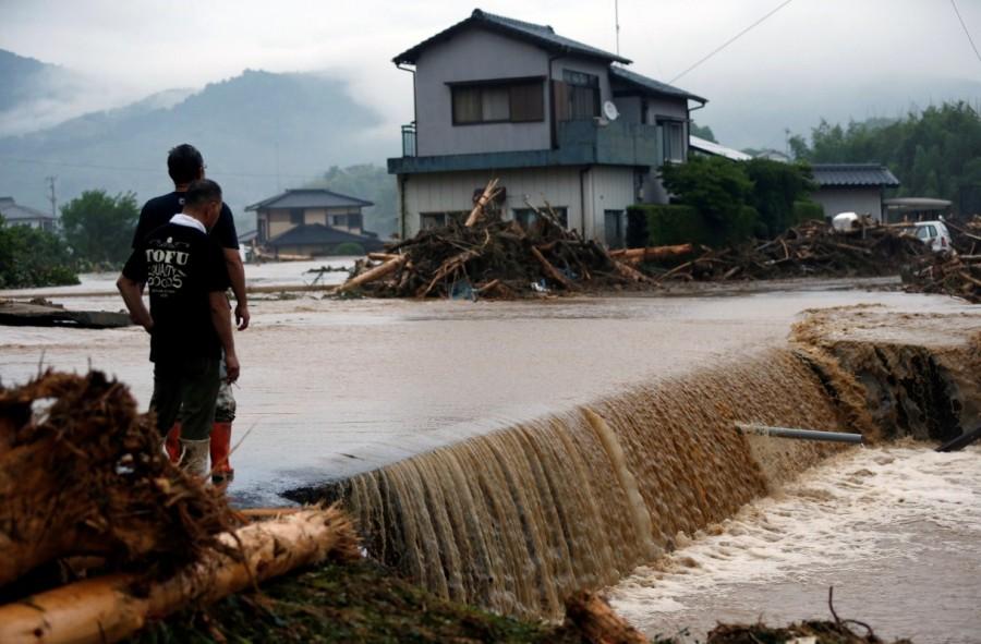 Local residents look at houses damaged by a swollen river after heavy rain hit the area in Asakura, Fukuoka Prefecture. Deadly deluge in Japan,Japan Deadly deluge,southwestern Japan,rains battered southwestern Japan,rain battered Japan,Torrential rain,Torrential rain in Japan