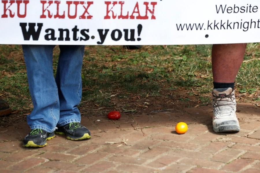 Members of the Ku Klux Klan, standing near a tomato and and an orange that had been thrown at them by counter-protesters, hold a sign as they rally in support of Confederate monuments in Charlottesville. Ku Klux Klan,Ku Klux Klan rally,Ku Klux Klan rally in Virginia,Confederate monuments