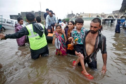 Fire officials and rescuers evacuate people from a flooded neighbourhood after heavy rains in Ahmedabad.