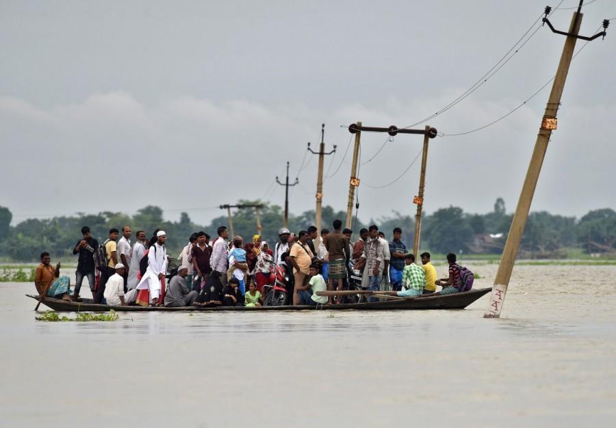 Villagers use a boat to cross a flooded road at Asigarh village in Morigaon district in Assam. Deadly monsoon,Deadly monsoon in India,Deadly monsoon rains,Massive floods,Massive floods in India