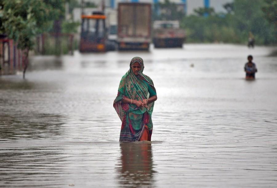 A woman wades through a road flooded by heavy rain in Ahmedabad. Deadly monsoon,Deadly monsoon in India,Deadly monsoon rains,Massive floods,Massive floods in India