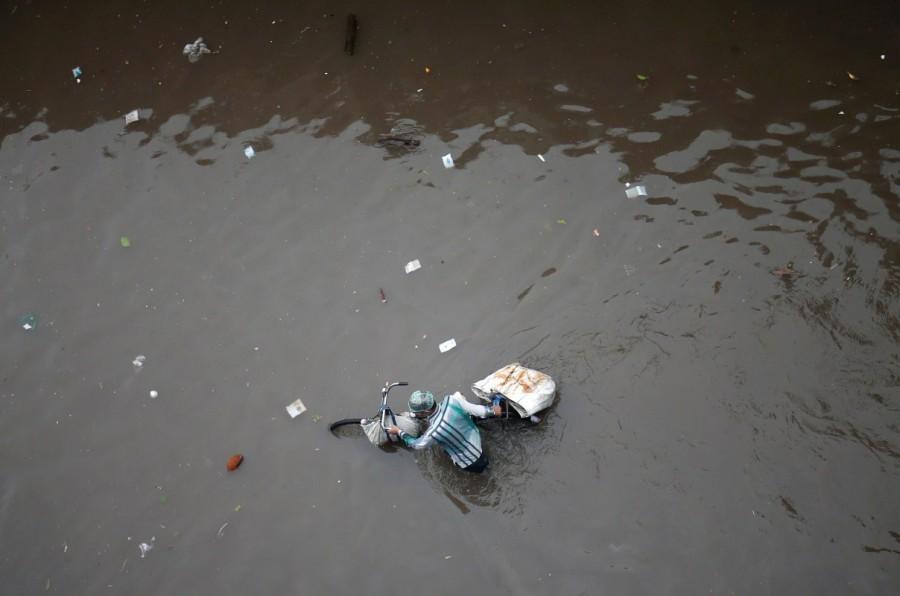 A man pushes his bicycle through a water-logged street after heavy rains in Ahmedabad, India. Deadly monsoon,Deadly monsoon in India,Deadly monsoon rains,Massive floods,Massive floods in India