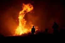 Firefighters work to put out a forest fire next to the village of Macao.