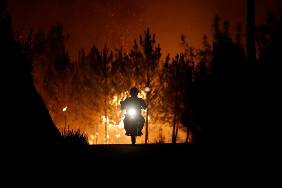 A firefighter is riding a motorbike away from a forest fire next to the village of Macao, near Castelo Branco. Portugal,Portugal battles raging wildfires,wildfires in Portugal,Portugal wildfires