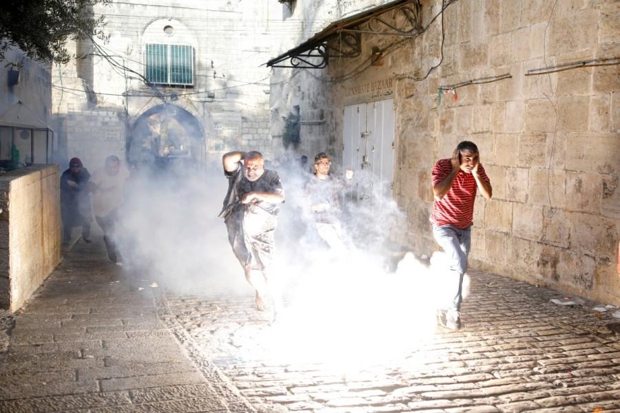 Palestinians react as a stun grenade explodes in a street at Jerusalem's Old city outside the compound known to Muslims as Noble Sanctuary and to Jews as Temple Mount, after Israel removed all security measures it had installed at the compound July 27, 2017. Jerusalem holy site,Jerusalem holy,Muslim worshippers,Jerusalem's Al-Aqsa Mosque,Israel