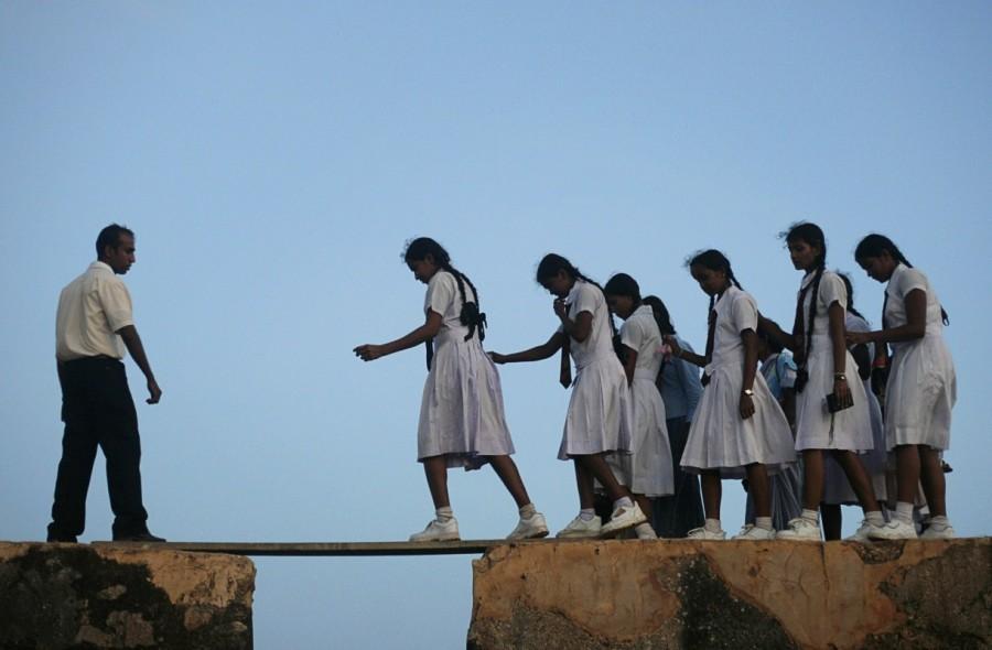 School girls walk across a plank on the walls of the 16th century Galle fort, Sri Lanka. Long journey to school,journey to school