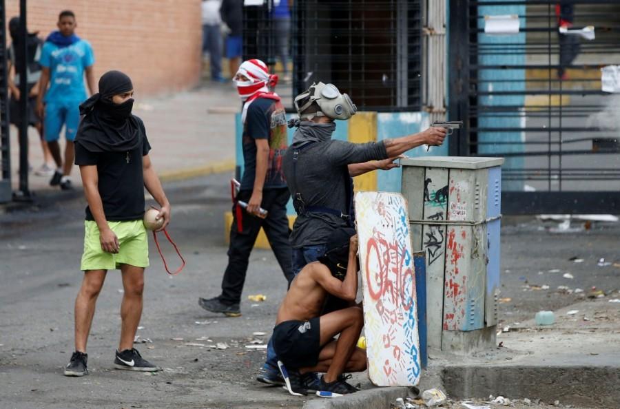 A demonstrator aims a pistol during clashes with government forces as the Constituent Assembly election was being carried out in Caracas, Venezuela, July 30, 2017. Venezuela election,Venezuela,protests over Venezuela election,Anti-government demonstrators,President Nicolas Maduro,Nicolas Maduro,Socialist Party