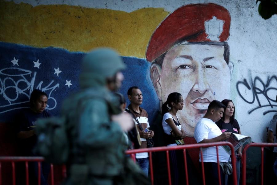 People wait in line next to an image of the late Venezuelan President Hugo Chavez before voting during the Constituent Assembly election in Caracas, Venezuela July 30, 2017. Venezuela election,Venezuela,protests over Venezuela election,Anti-government demonstrators,President Nicolas Maduro,Nicolas Maduro,Socialist Party