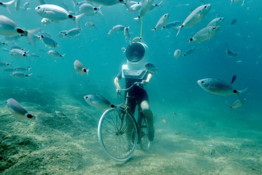 A woman dives and pretends to ride a bike in Underwater Park in Pula, Croatia, August 1, 2017. Croatia,Playing underwater,Playing underwater in Croatia