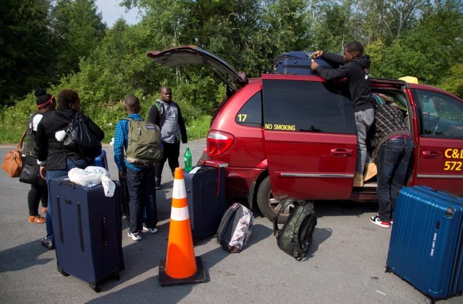 A refugee family claiming to be from Haiti take their luggage from their taxi as they arrive at the U.S.-Canada border. About 400 to 500 Haitian asylum seekers walked into the province of Quebec in the past week, said Marjorie Villefranche, director of the Maison d'Haiti, a community group in Montreal that is helping to settle the newcomers. Canada from the U.S.,Canada-U.S. border,U.S. border,Quebec