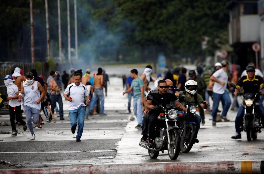 Demonstrators run and ride their motorcycles near Fuerte Paramacay military base during clashes with security forces in Valencia, Venezuela. Venezuela,Venezuela quells attack,Venezuela attack on military base,South American nation