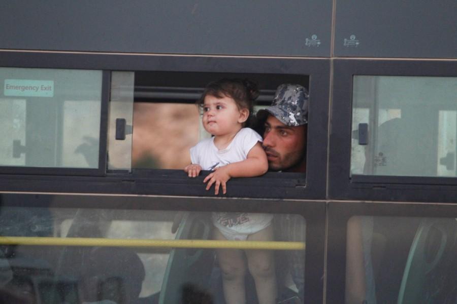 A Syrian man with a child is seen in a bus in Jroud Arsal, Lebanon. Syrians evacuate Lebanon border,Lebanon border camps,Syrian militants,Syrian militants and refugees,Syrian refugees,Nusra Front militants