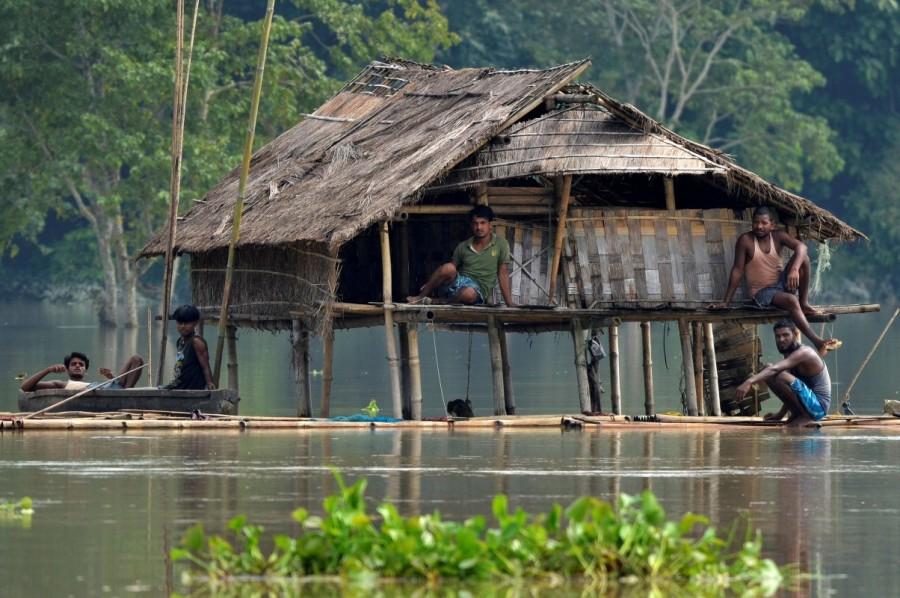 Villagers take shelter in a partially submerged house following floods at Baghmari village in Nagaon district, in the northeastern state of Assam, India. Monsoon floods across South Asia,floods across South Asia,monsoon rains in Nepal,Floods in Nepal,Floods in Bangladesh,Floods in India
