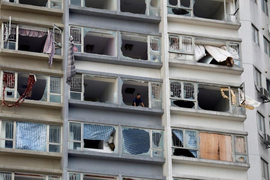 A man looks out from inside an apartment where some windows have been broken by typhoon Hato in Macau. Typhoon Hato,Hong Kong,typhoon,Macau,Hong Kong and Macau