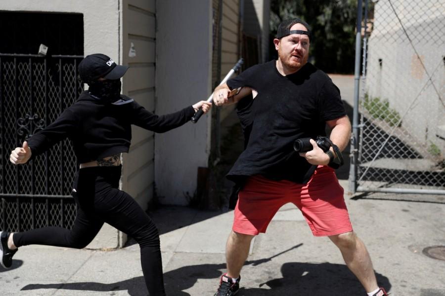 A photographer is being attacked by a masked demonstrator in Martin Luther King Jr. Civic Center Park during a cancelled No Marxism in America rally and counter-protest in Berkeley, California. No Marxism,No Marxism rally,Rally Against Hate,No Marxism in America