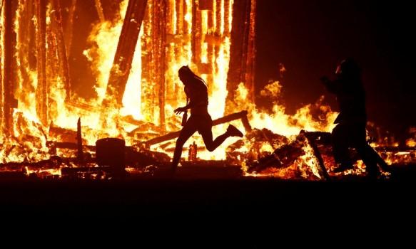 A Burning Man participant evades a chasing firefighter and runs into the flames of the 