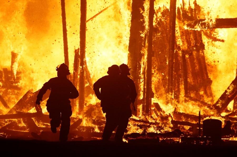 Firefighters are forced to abandon their attempted rescue of a Burning Man participant (body seen at lower left rear) who ran into the flames of the "Man Burn" when the structure began to crumble and fall around them at the annual Burning Man arts and music festival in the Black Rock Desert of Nevada, U.S. September 2, 2017. Burning Man festival,Burning Man festival 2017,Burning Man,Man runs into flames,firefighters