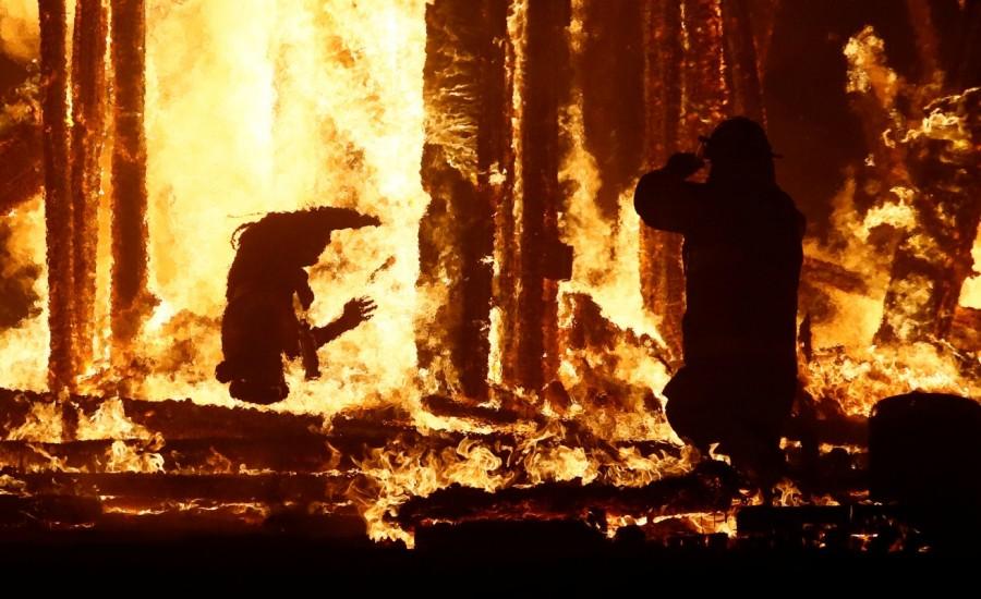 A Burning Man participant (L) evades a chasing firefighter and falls into the flames of the "Man Burn" after evading the attempted tackles of multiple rangers and law enforcement personnel at the annual Burning Man arts and music festival in the Black Rock Desert of Nevada, U.S. September 2, 2017. Burning Man festival,Burning Man festival 2017,Burning Man,Man runs into flames,firefighters
