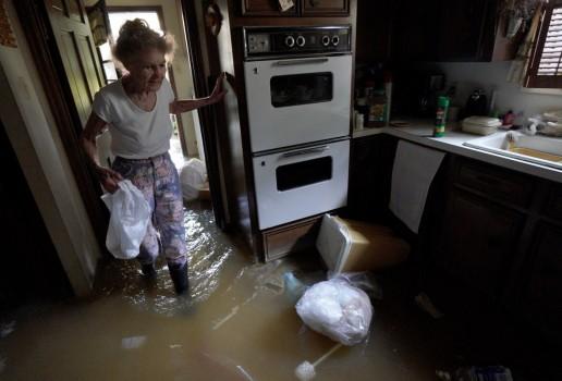 Nancy McBride collects items from her flooded kitchen as she returned to her home for the first time in Houston.