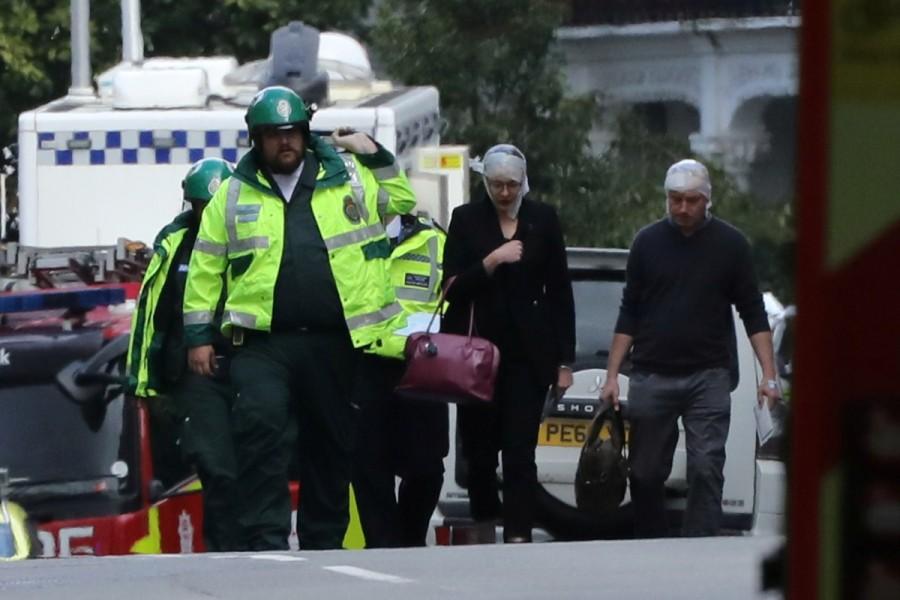An injured woman is led away after an incident at Parsons Green underground station in London. London underground,London Underground explosion,london underground,London underground blast,London Underground Station,Blast at London underground