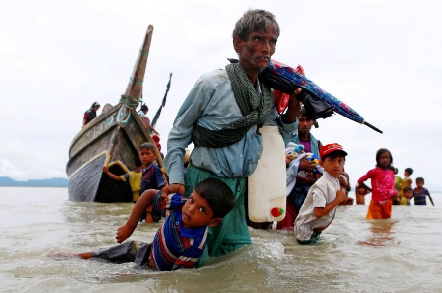A Rohingya refugee man pulls a child as they walk to the shore after crossing the Bangladesh-Myanmar border by boat through the Bay of Bengal in Shah Porir Dwip, Bangladesh, September 10, 2017. Myanmar,Myanmar violence,Muslim Rohingya,Rohingya flee Myanmar violence