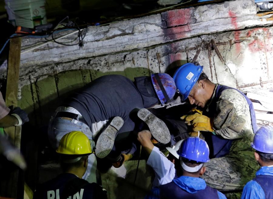 Members of a rescue team hold a fellow rescuer from the Topos volunteer search and rescue group by his feet during the search for students, September 21, 2017. Mexico races to find survivors,Rescuers labor,Enrique Rebsamen School,earthquake