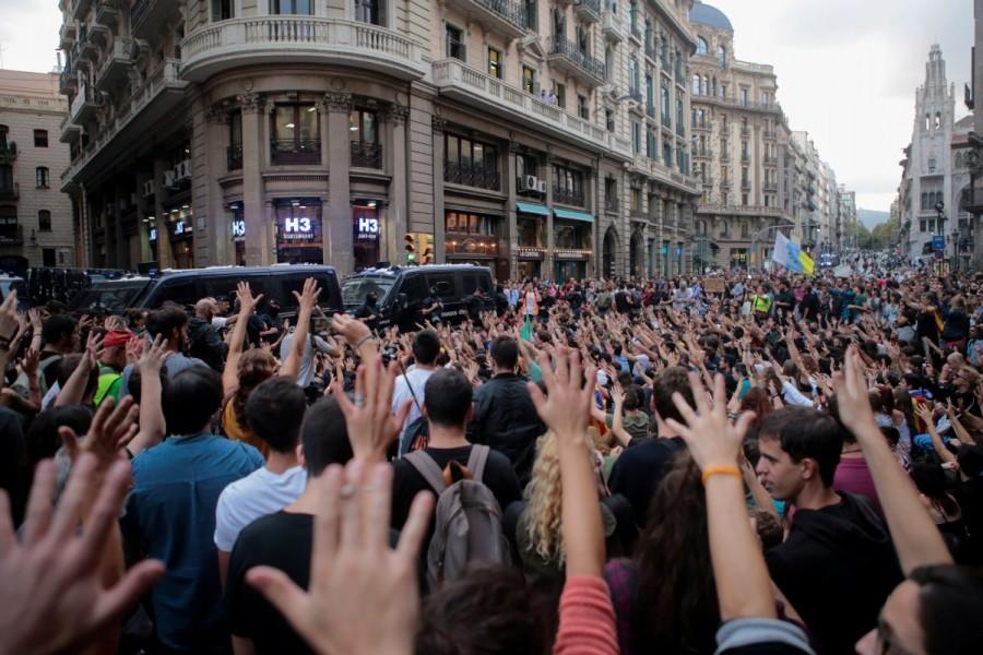 People raise hands during a protest as Catalan regional police officers stand guard outside National Police station, in Barcelona. Catalonia,Catalonia protests,Spanish police,violent secession vote