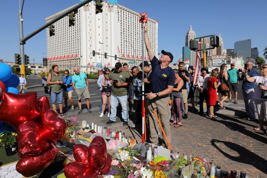 A member of the FBI Evidence Response Team works to map the scene near a memorial in the middle of Las Vegas Boulevard. Las Vegas shooting aftermath,Las Vegas aftermath,Las Vegas shooting,Las Vegas,Aftermath in Las Vegas,Las Vegas in Aftermath