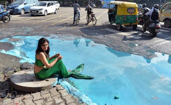Sonu Gowda poses as a mermaid in front of a pothole where artist Baadal Nanjundaswamy created an art work on Cubbon Road.