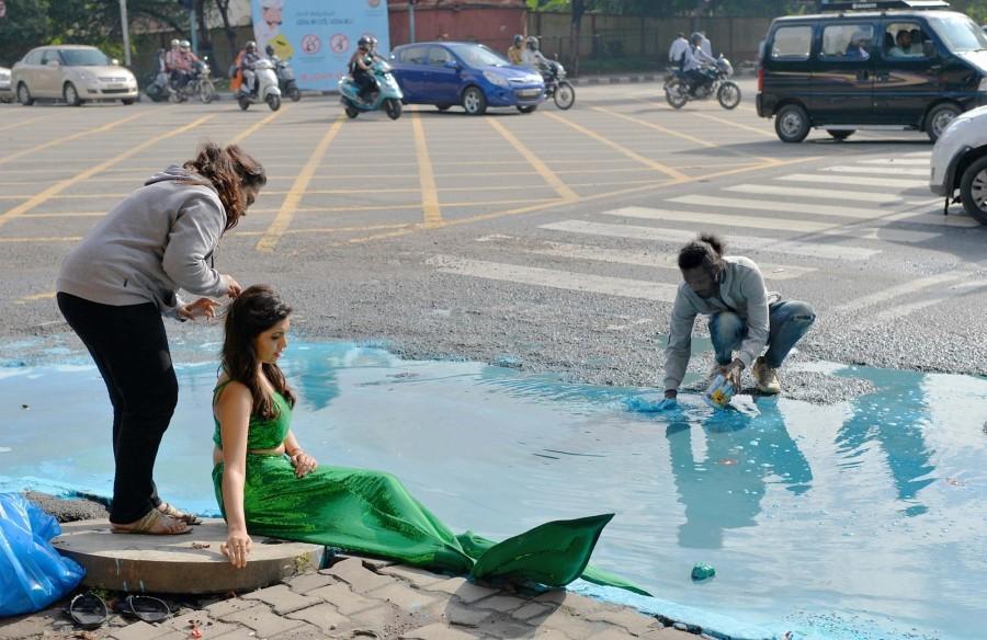 Actress Sonu Gowda poses as a mermaid in front of a pothole where artist Baadal Nanjundaswamy created an art work on Cubbon Road in Bengaluru. Sonu Gowda,actress Sonu Gowda,pothole,bangalore pothole,Bangalore rain,Sonu Gowda poses near pothole
