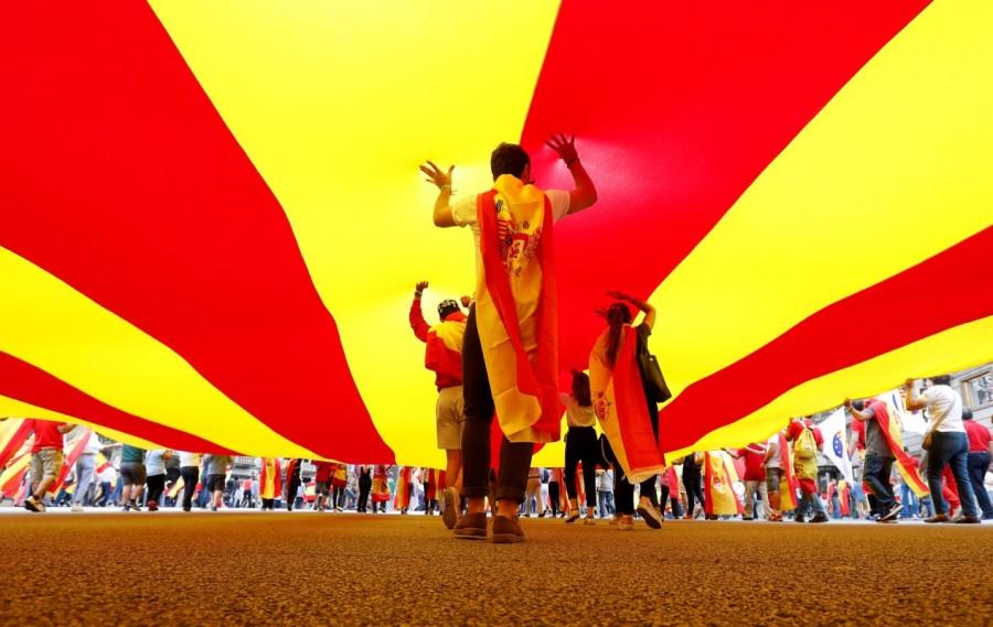 People walk under a huge Catalan flag during Spain's National Day in Barcelona. Spain celebrates National Day,National Day,Spain National Day