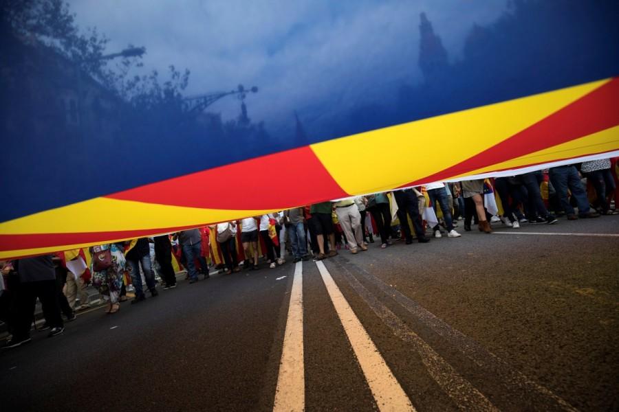 People walk with a Spanish, European and Catalan flag during Spain's National Day in Barcelona. Spain celebrates National Day,National Day,Spain National Day
