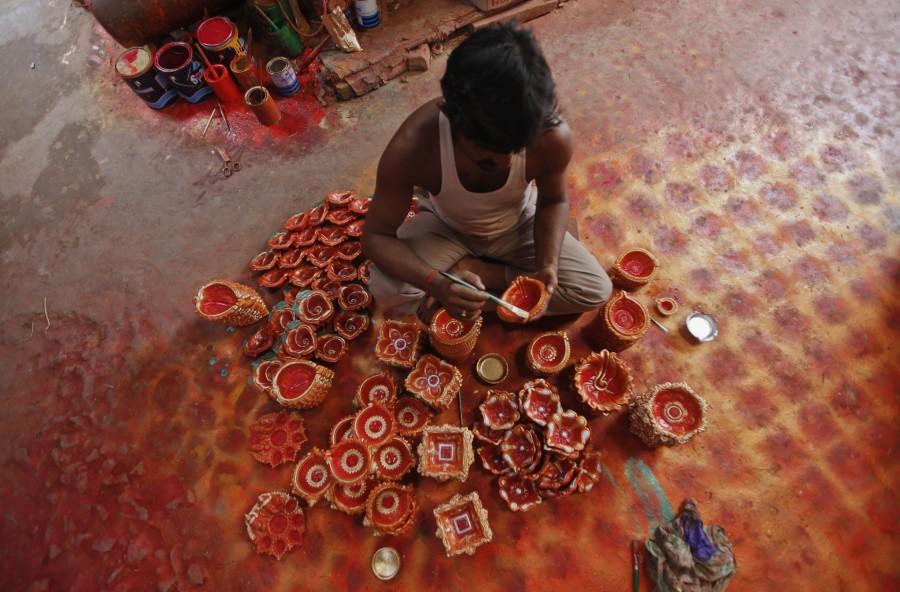 A potter paints clay lamps, which will be filled with oil and lit during the Lakshmi Puja and Diwali festivals, inside a workshop in Kolkata. Diwali 2017,Happy Diwali 2017,Happy Diwali,festival of light,significance of festival of lights,People gears for festival of light,People gears for Diwali,People gears for Diwali 2017,happy diwali,Diwali quotes,Diwali wishes,Diwali greetings