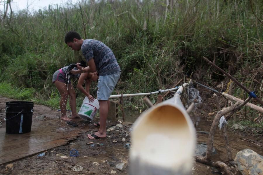 Madelyn Matos (L) and her boyfriend Jan Marcos Chaparro do their laundry with mountain spring water, after Hurricane Maria hit the island, in Corozal. Puerto Ricans,drinking water,search for water,Hurricane Maria hit,Hurricane Maria