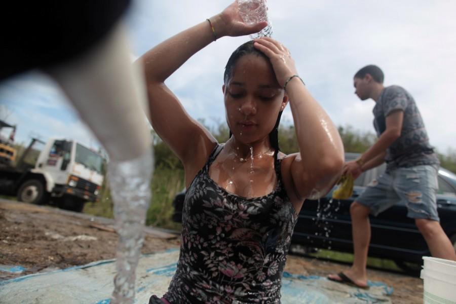 Madelyn Matos washes her hair as her boyfriend Jan Marcos Chaparro cleans his car with mountain spring water, after Hurricane Maria hit the island, in Corozal. Puerto Ricans,drinking water,search for water,Hurricane Maria hit,Hurricane Maria