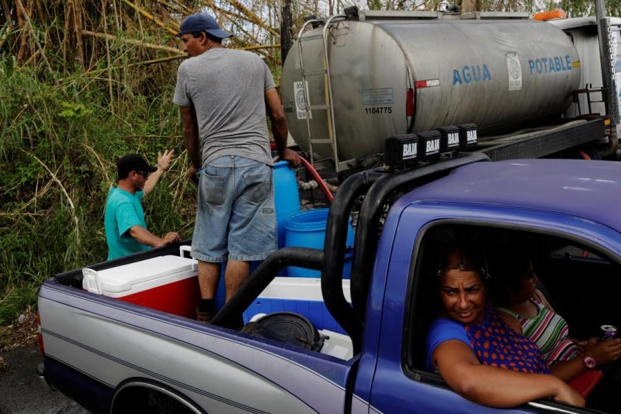 A family waits as a man fills drums with potable water brought to their small mountain community once a day after Hurricane Maria crippled utilities near Guayama. Puerto Ricans,drinking water,search for water,Hurricane Maria hit,Hurricane Maria