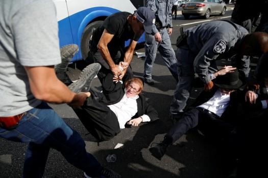 Israeli policemen carry away ultra-Orthodox Jewish men as they try to block a road during a protest against the detention of members of their community who failed to report to a military recruiting office, near Modiin, Israel.