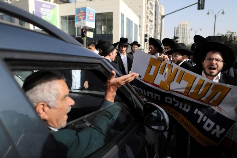 A driver argues with ultra-Orthodox Jewish men as they protest against the detention of members of their community who failed to report to a military recruiting office, in Jerusalem. The placard in Hebrew reads, "Fans of those imprisoned from the Torah world". Ultra-Orthodox protest,Ultra-Orthodox,Ultra-Orthodox protest against the detention,military recruiting office