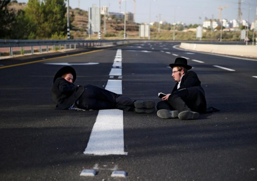Ultra-Orthodox Jewish men sit on a road during a protest against the detention of members of their community who failed to report to a military recruiting office, near Modiin. Ultra-Orthodox protest,Ultra-Orthodox,Ultra-Orthodox protest against the detention,military recruiting office