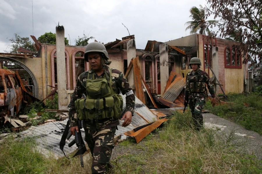 Soldiers walk past a damaged house after government troops cleared the area. Philippine city,pro-Islamic State,pro-Islamic State rebels