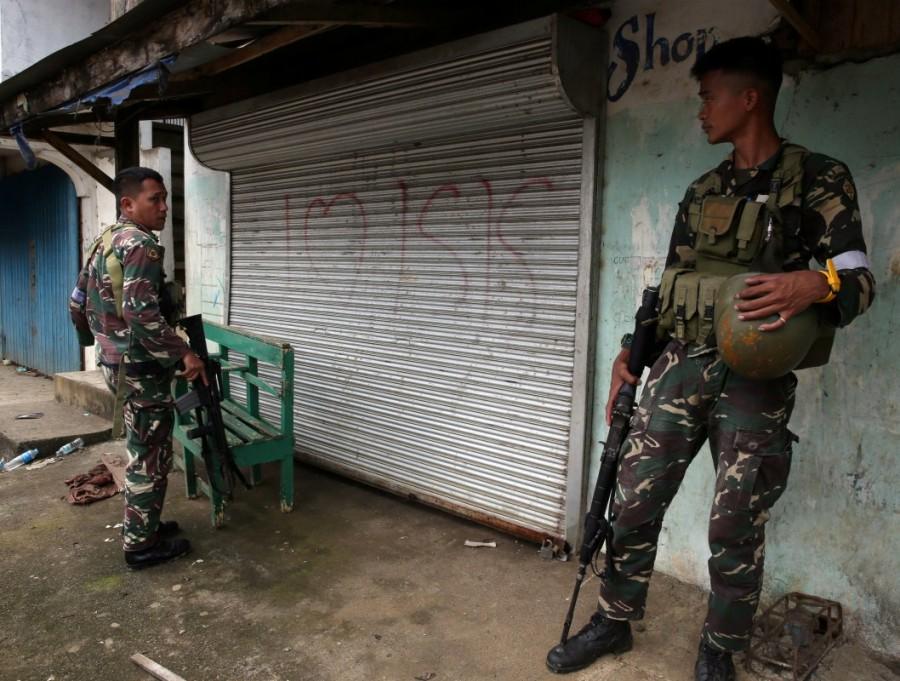 Soldier stand on guard in front of a door with "I love ISIS" graffiti after government troops cleared the area. Philippine city,pro-Islamic State,pro-Islamic State rebels