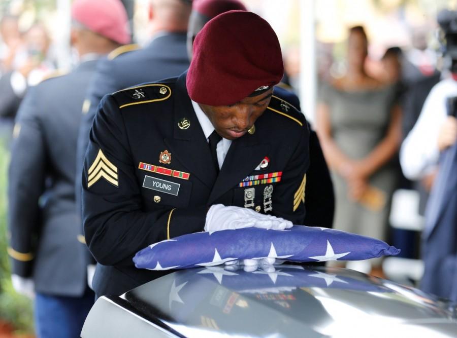 An honor guard member touches an American flag to the coffin of U.S. Army Sergeant La David Johnson. Sgt. La David Johnson,Sgt. La David Johnson Funeral,Sgt. La David Johnson Funeral pics,Sgt. La David Johnson Funeral images,Sgt. La David Johnson Funeral stills,Sgt. La David Johnson Funeral pictures,Sgt. La David Johnson Funeral photos