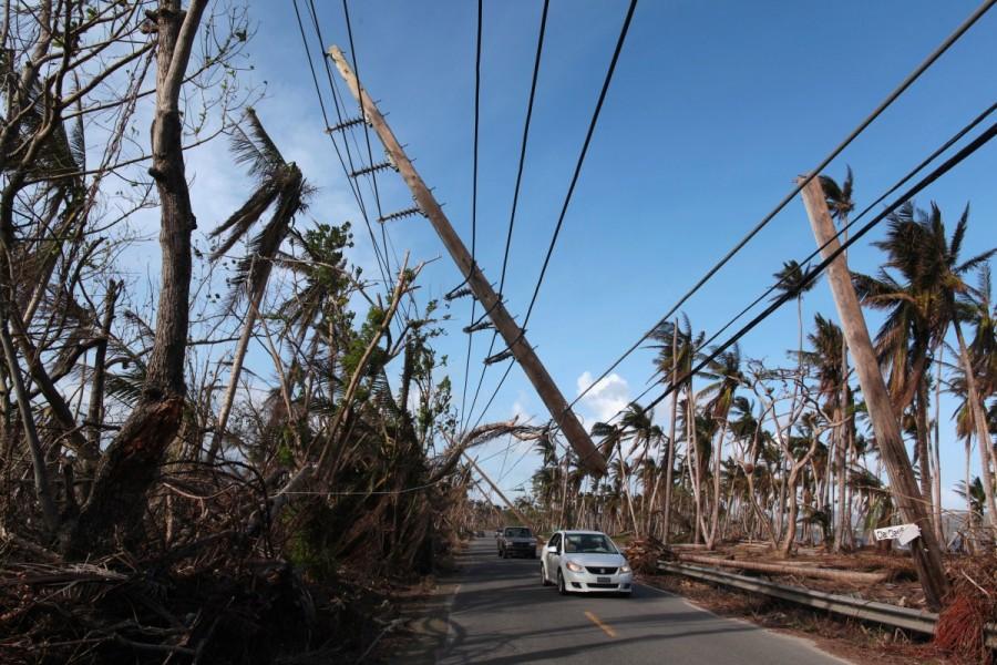Cars drive under a partially collapsed utility pole in Naguabo. Puerto Rico,Hurricane Maria,Puerto Rico after Hurricane Maria