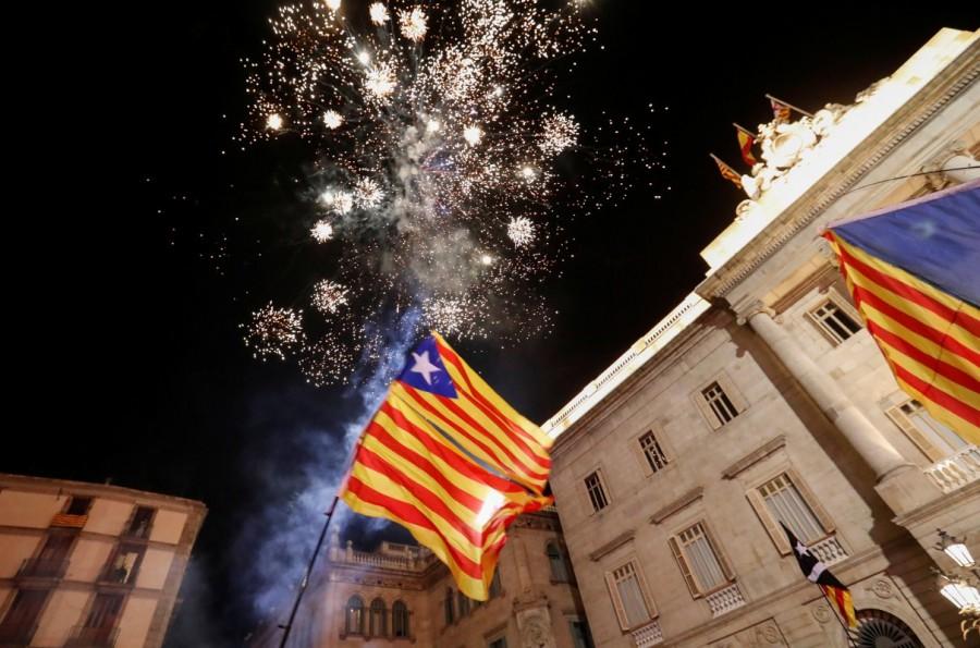 Catalan separatist flags are held up as fireworks go off in Sant Jaume Square in front of the Catalan regional government headquarters during celebratrions after the Catalan regional parliament declared independence from Spain in Barcelona, Spain, October 27, 2017. Catalonia declares independence,Catalonia,Catalonia independence,catalonia independence vote,Spain Catalonia rift,spain and catalonia,Catalonia unilaterally,Spain