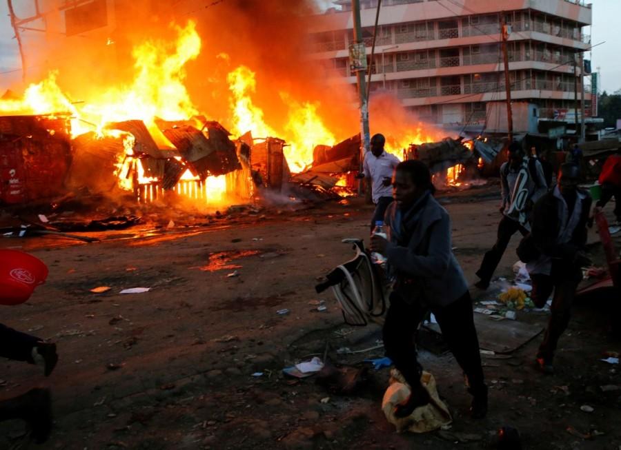 People run past properties that were set on fire by rioters in Kawangware slums in Nairobi. Kenyan opposition,Kenyan leader,deadly violence,deadly violence in Kenya,Kenya deadly violence
