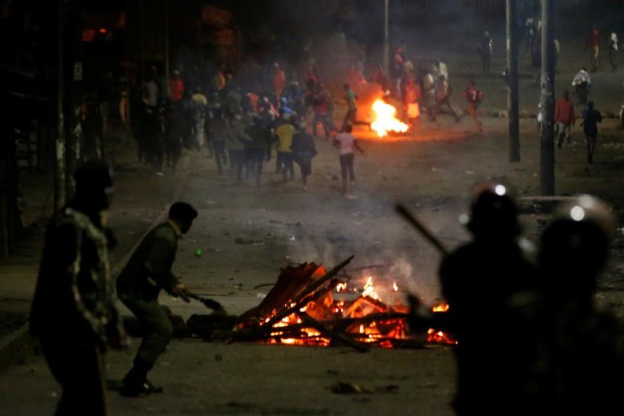 Anti-riot police stand behind barricades set on fire by opposition supporters in the slum area of Mathare in the capital Nairobi. Kenyan opposition,Kenyan leader,deadly violence,deadly violence in Kenya,Kenya deadly violence