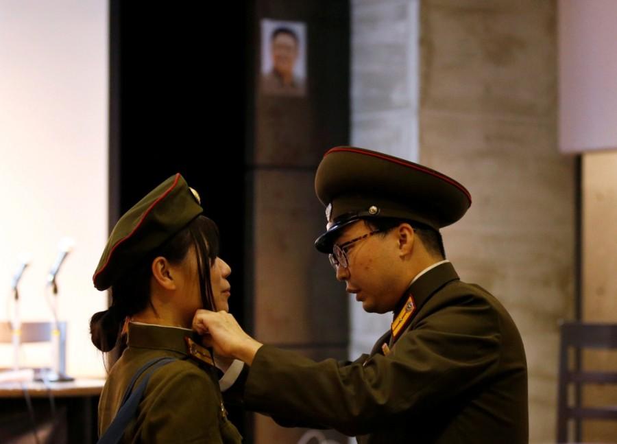 North Korea fans dressed as the Korean People's Army adjust their clothes in front of a portrait of North Korea's late leader Kim Jong Il. North Korea fan club,North Korea,North Korea fan club in Tokyo